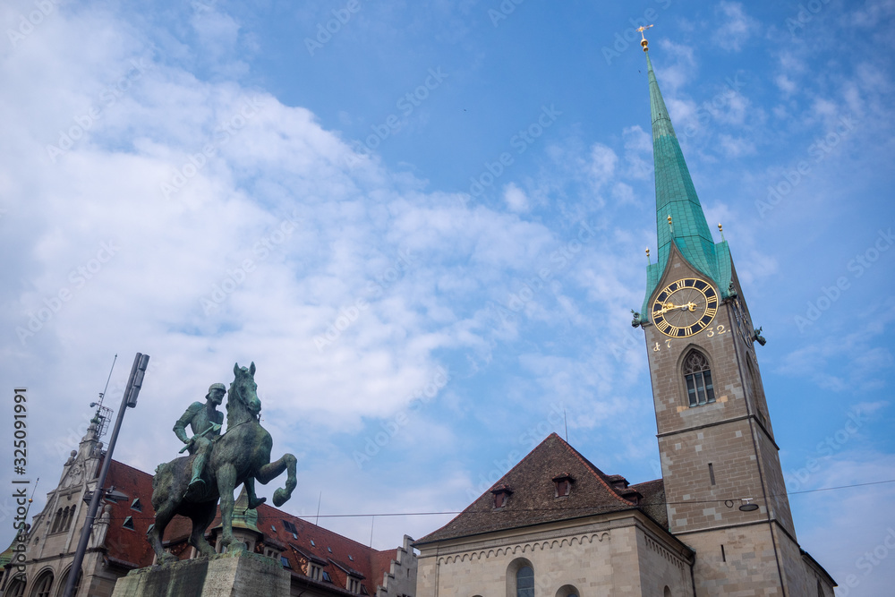 The beautiful tower of Fraumunster and statue on blue sky with cloud background, copy space, Zurich, Switzerland The beautiful tower of Fraumunster and statue on blue sky with cloud background, copy space, Zurich, Switzerland