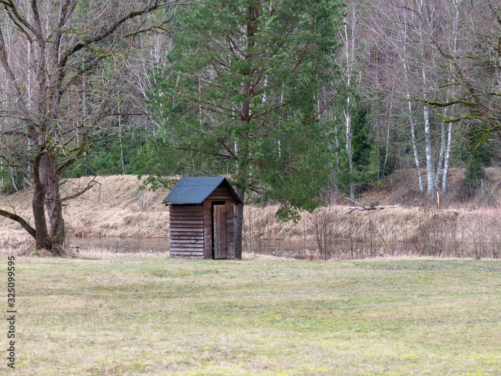 landscape with wooden toilet on the river bank landscape with wooden toilet on the river bank