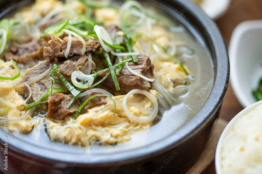 One big set of galbitang, korean style beef soup, serve with many slide dish and rice on wood table with nature light. For food issue. One big set of galbitang, korean style beef soup, serve with many slide dish and rice on wood table with nature light. For food issue.