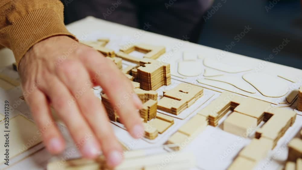 Close up of architect hand checking city model concept Close up of architect hand checking city model concept