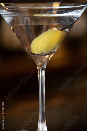 Super close up of a martini cocktail whit a big green olive inside. The perfect drink for the classy connoisseur. alcoholic beverages.