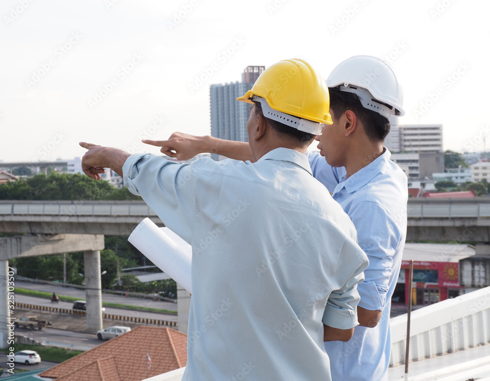 asian male engineer or foreman and architects Asian people are pointing to highrise building.