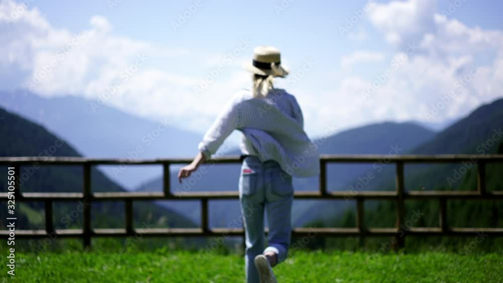 Back view of young woman tourist running to viewpoint with breathtaking nature view and raising hands while feeling excited with summer trip, female traveler enjoying journey to Austria. Slow motion Back view of young woman tourist running to viewpoint with breathtaking nature view and raising hands while feeling excited with summer trip, female traveler enjoying journey to Austria. Slow motion