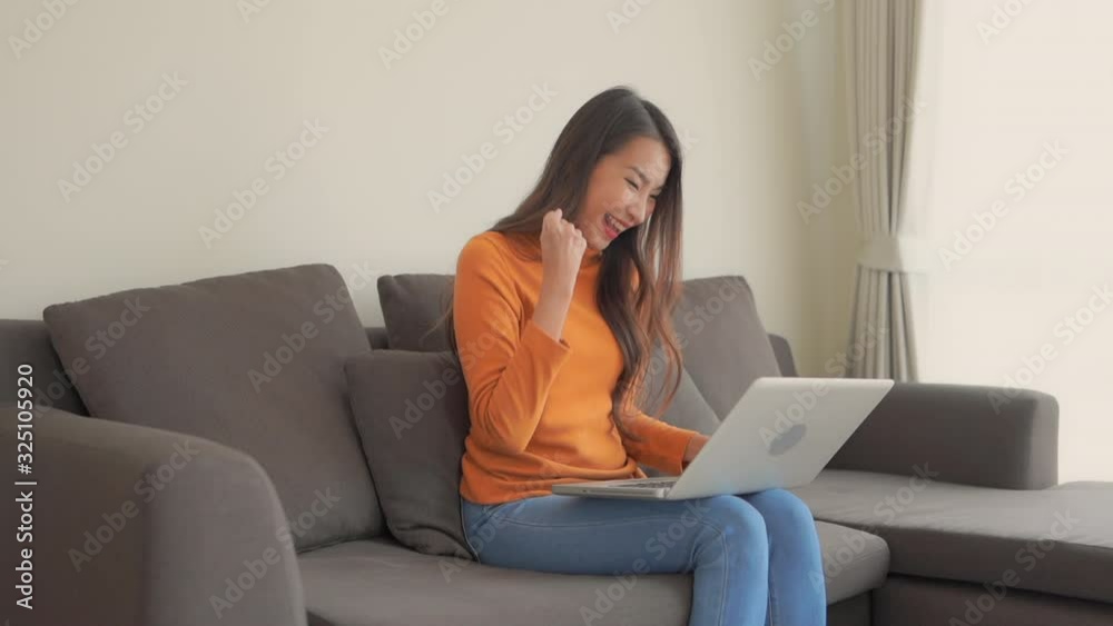 Slim, successful asian woman in an orange turtleneck working on laptop Slim, successful asian woman in an orange turtleneck working on laptop
