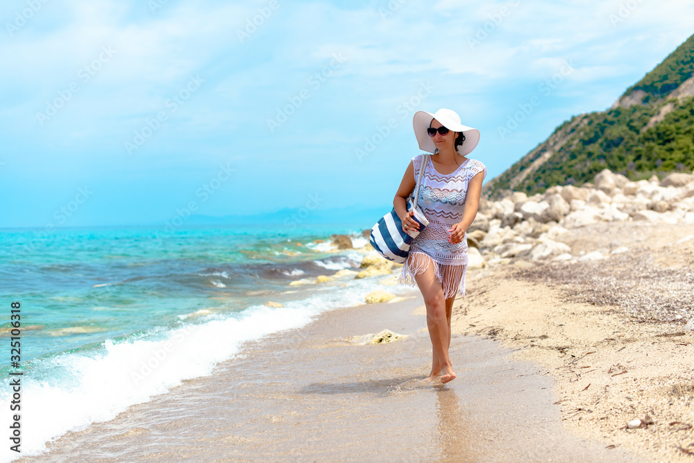 A women in white beachwear is walking by the water