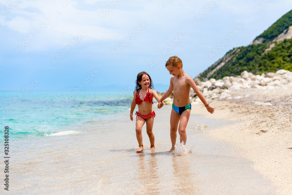 A little girl and boy are walking by the water