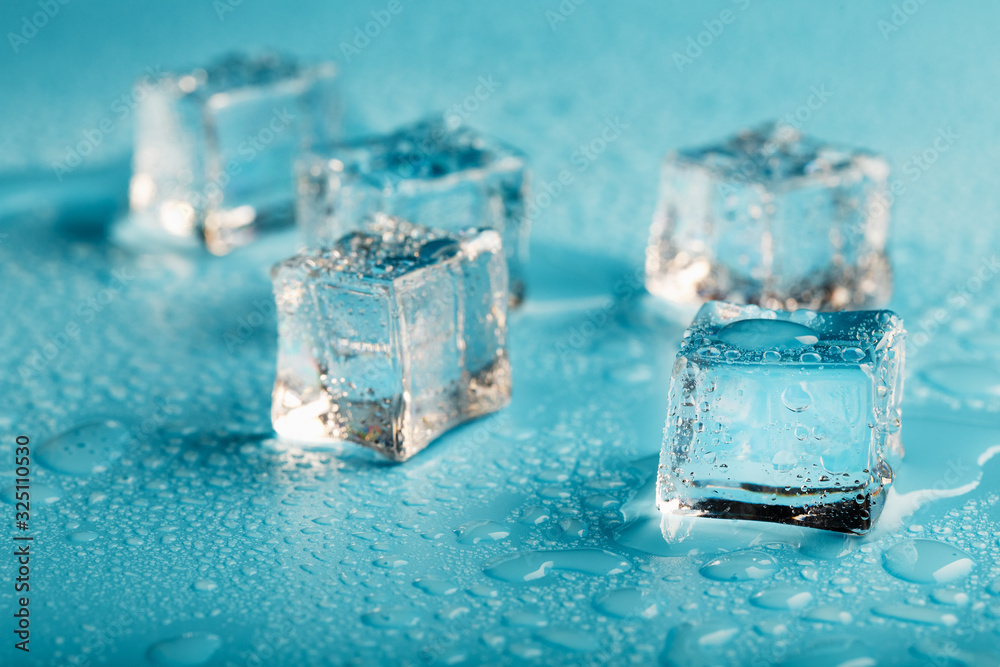 Ice cubes are scattered with water drops scattered on a blue background. Ice cubes are scattered with water drops scattered on a blue background.
