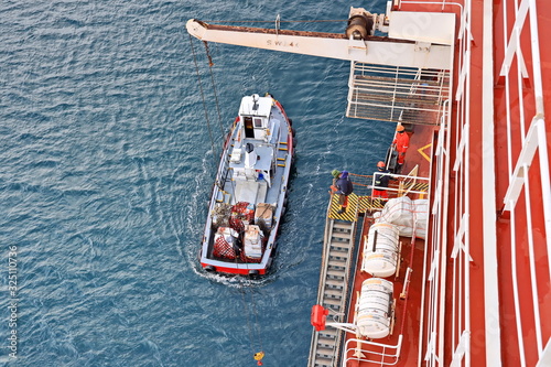 Foto Loading of supplies and provisions from the boat to the ship on the roadstead