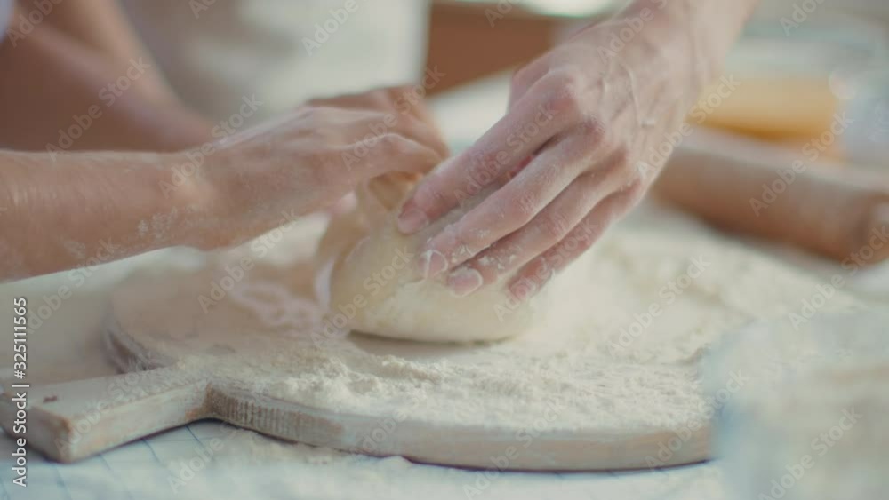 Mother hands helping daughter to knead dough on table at home Mother hands helping daughter to knead dough on table at home