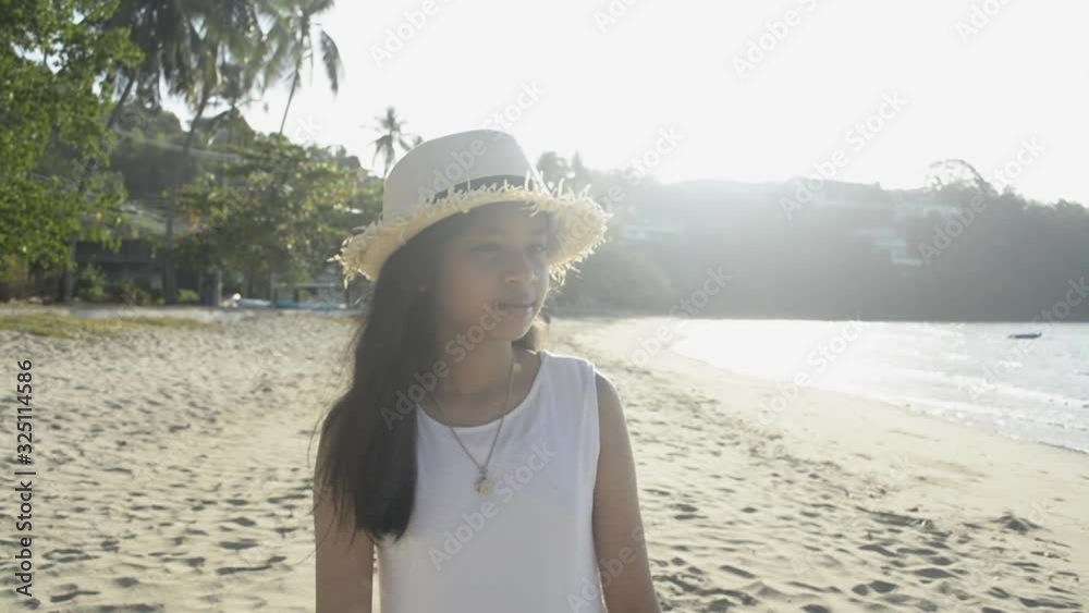 Asian cute girl wearing straw hat and casual dress walking on the beach under sunlight in the morning. Slow motion. Asian cute girl wearing straw hat and casual dress walking on the beach under sunlight in the morning. Slow motion.
