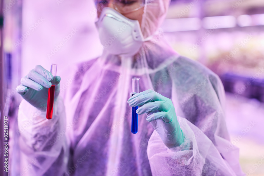 Close-up of chemist holding two test tubes with different liquids in his hands in the lab