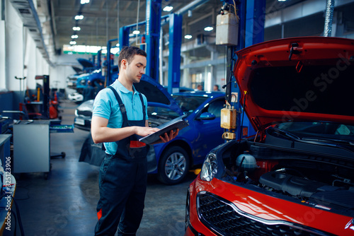 Worker with a checklist, car service station