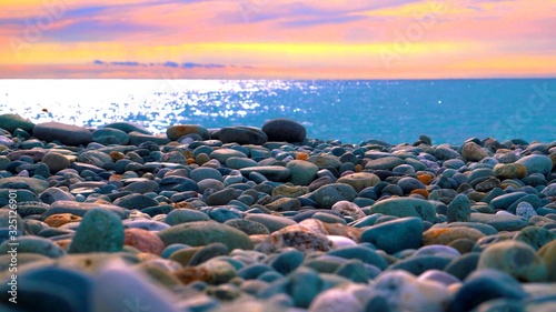 Des galets colorés sur une plage pendant un coucher de soleil © Shenzen Photo Lab