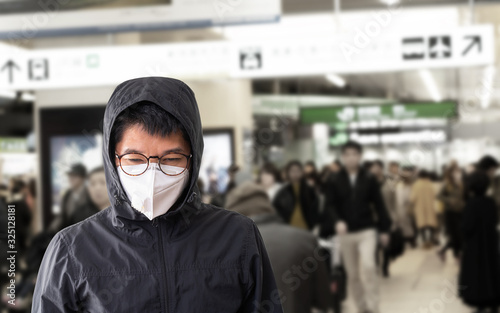 Asian man wearing surgical mask to prevent flu disease Corona virus with blurred image of crowded