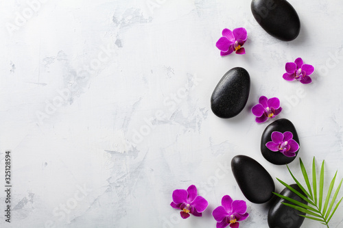 Spa composition with flowers, green leaves and massage stone on white background top view. Beauty treatment and relaxation concept. Flat lay. .