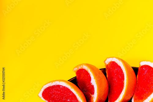 Fresh and juicy grapefruit on the black plate with yellow background
