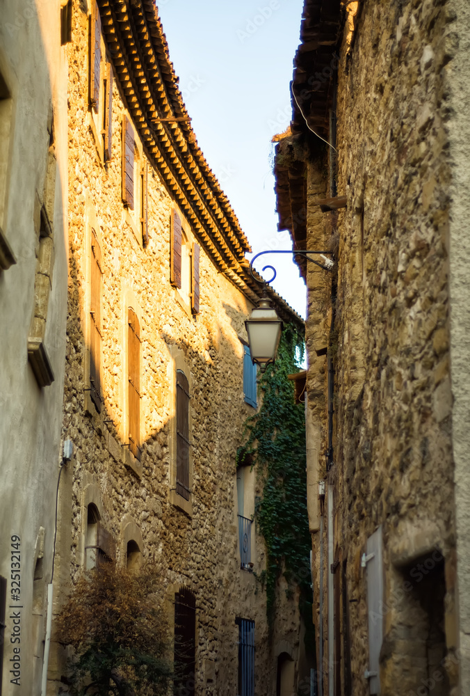 Vertical picture of scenic stone narrow street with medieval lantern in Lourmarin, one of the most beautiful villages of France located in Luberon, heart of Provence. Popular tourism destination.