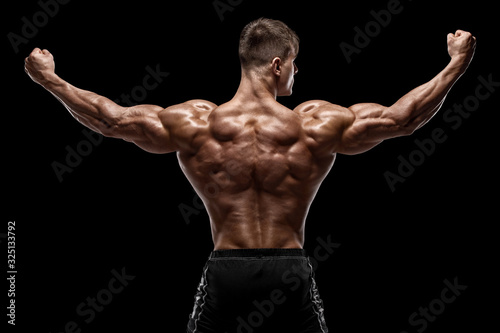 Muscular man showing back muscles, isolated on black background. Strong male rear view photo