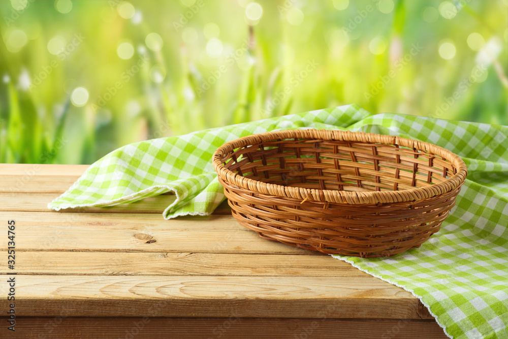 Empty basket with tablecloth on wooden table over green bokeh background. Spring and easter mock up for design. Empty basket with tablecloth on wooden table over green bokeh background. Spring and easter mock up for design.