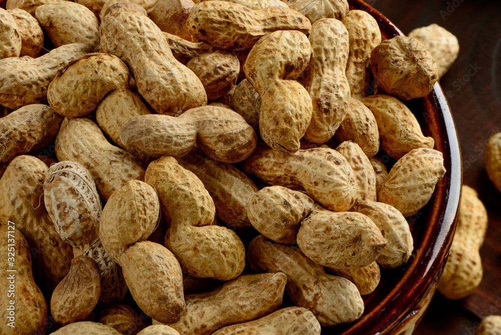 Peanuts in a bowl on the dark background. Peanuts in a shell. Healthy food. Peanuts in a bowl on the dark background. Peanuts in a shell. Healthy food.