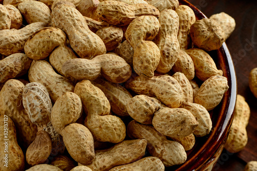 Peanuts in a bowl on the dark background. Peanuts in a shell. Healthy food.