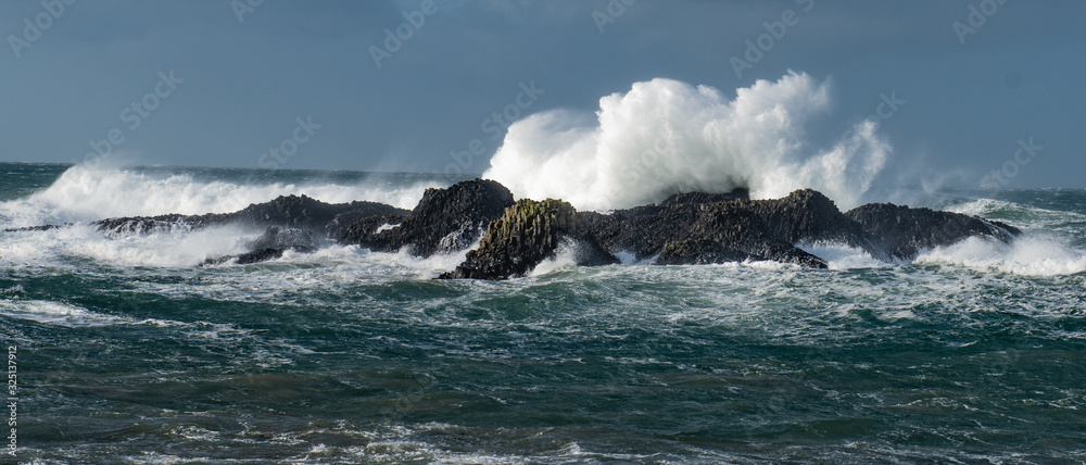 Massive waves crash over the rocks at Ballintoy Harbour, Causeway Coast, Northern Ireland