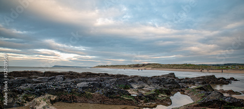 Looking across rock pools to a long beach and sand dunes