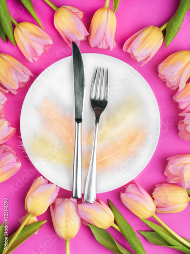Easter table cutlery with tulips, feathers on pink background © artemidovna