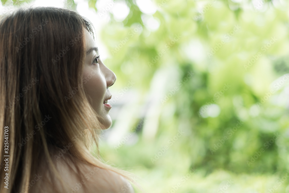 closeup portrait asian woman looking at space from behide against green tree nature background. selective focus closeup portrait asian woman looking at space from behide against green tree nature background. selective focus