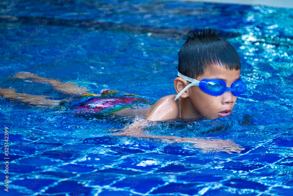 Asian boy floating and swimming in pool. Show up only face. blue refreshing water.