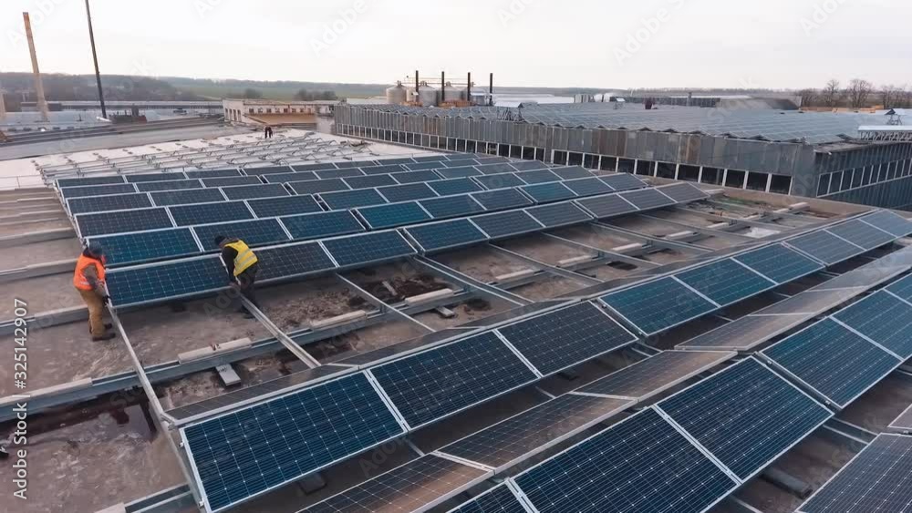 Workers installing solar panels on the roof. Modern solar panels to produce clean energy. Installation of photovoltaic panels. Aerial view. Workers installing solar panels on the roof. Modern solar panels to produce clean energy. Installation of photovoltaic panels. Aerial view.