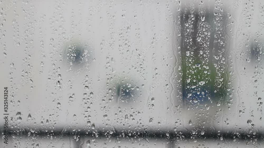Close-up of water droplets on glass, Rain Rain, Go Away. Large rain drops strike a window pane during a summer shower.