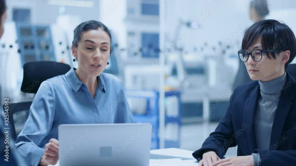 Modern Factory Office Meeting Room: Confident Female Project Manager Talks to Diverse Team of Engineers, Businesspeople and Investors Sitting at the Conference. Manufacturing Facility Optimization Modern Factory Office Meeting Room: Confident Female Project Manager Talks to Diverse Team of Engineers, Businesspeople and Investors Sitting at the Conference. Manufacturing Facility Optimization