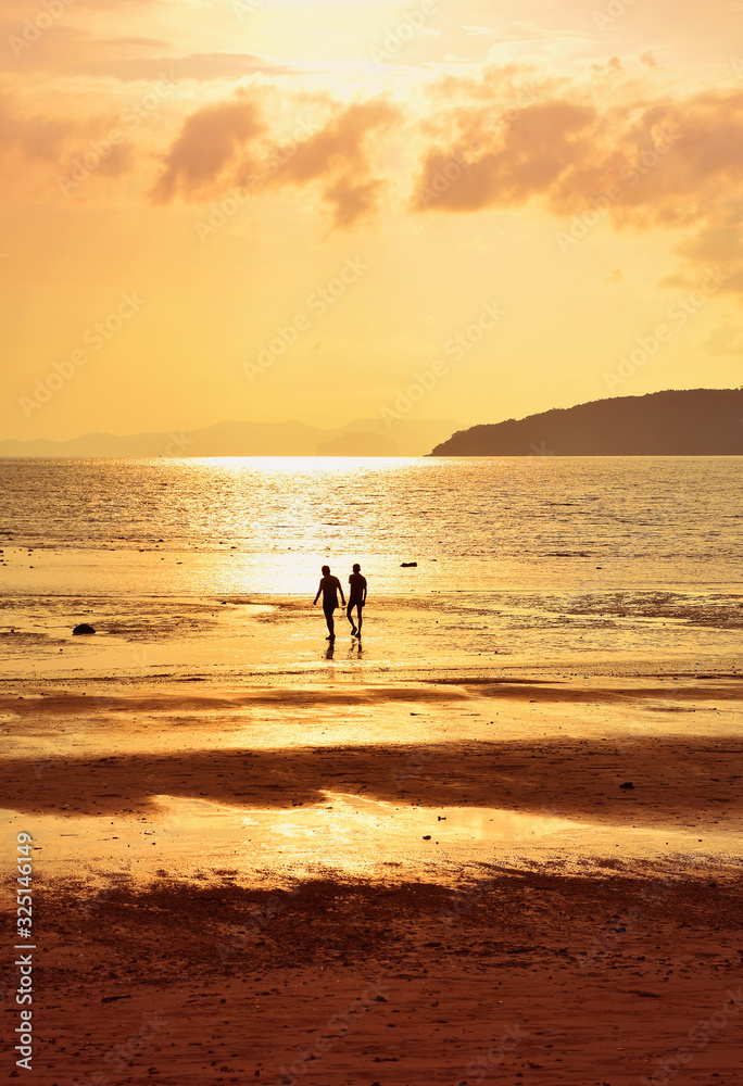Silhouette of two people on sunset sea shore