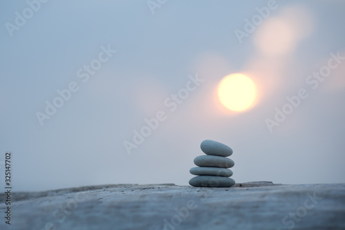Canvas Print pyramid of stones by the sea at dawn. balanced zen stones.