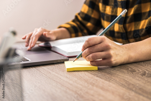 quick note. close up hands of a businesswoman, student or freelancer in yellow shirt making a note on sticky note