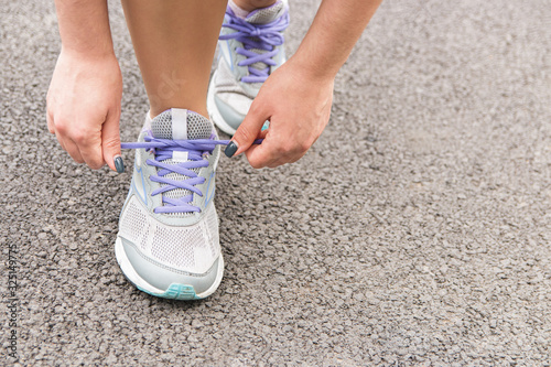 time for running. closeup view of woman tying shoelaces on asphalt