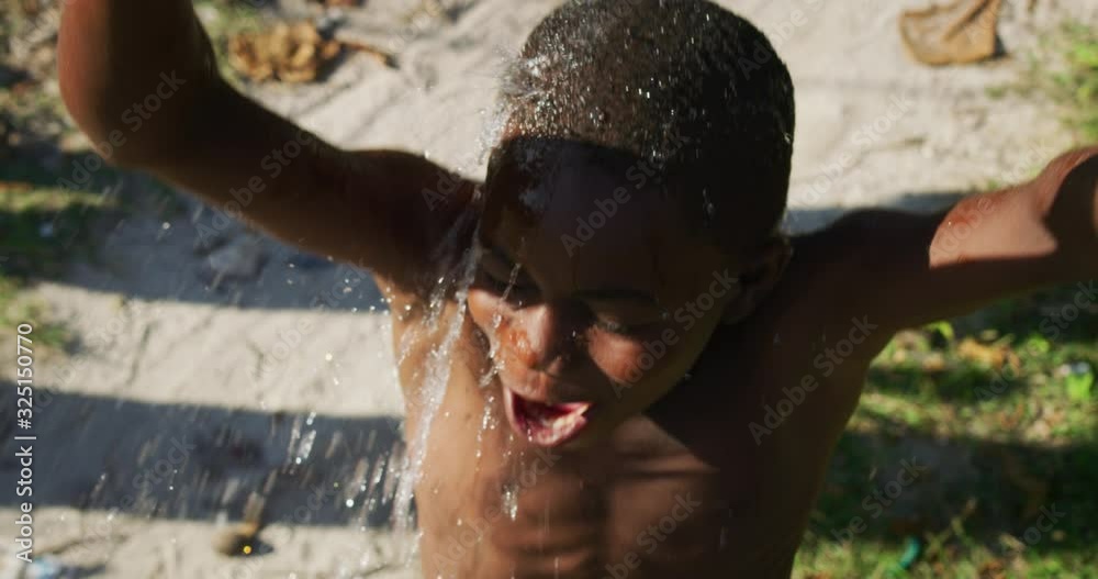 Authentic shot of happy carefree rural african little boy is having fun to play with water in a hot sunny day. Concept: freedom, charity ,life, happiness, authenticity,childhood Authentic shot of happy carefree rural african little boy is having fun to play with water in a hot sunny day. Concept: freedom, charity ,life, happiness, authenticity,childhood