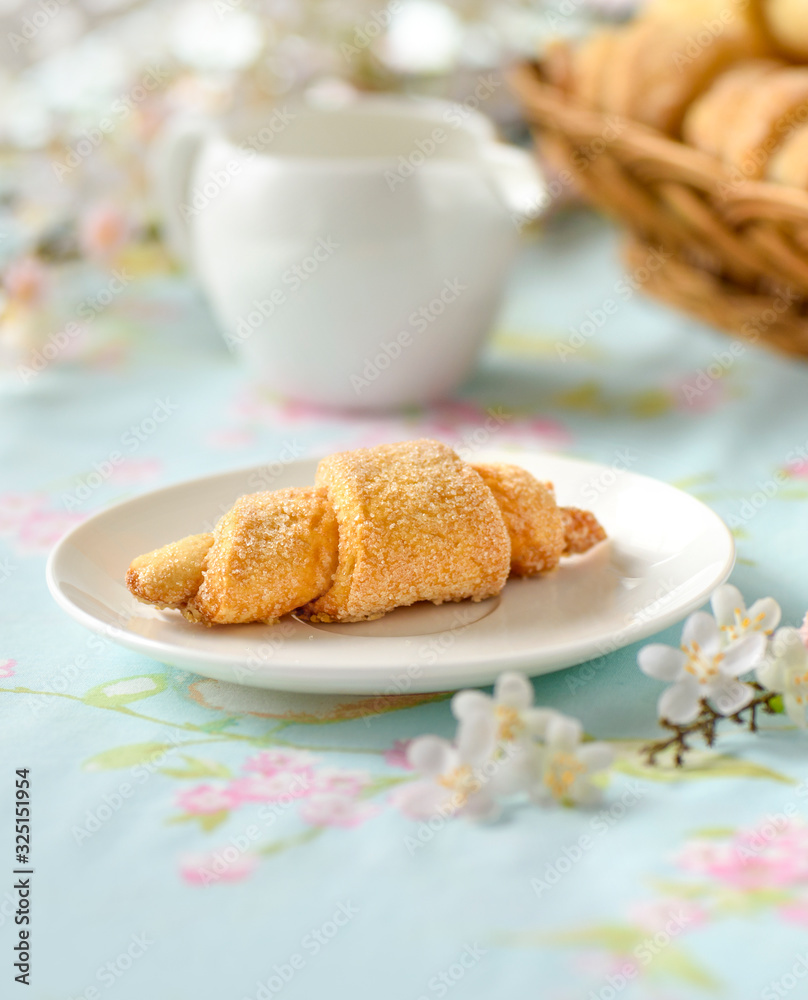One croissant on a table with spring flowers One croissant on a table with spring flowers