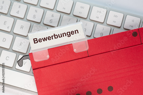 Roter Hängehefter mit Reiter und dem Text: Bewerbungen. Der Ordner liegt auf einem Computer Keyboard. photo