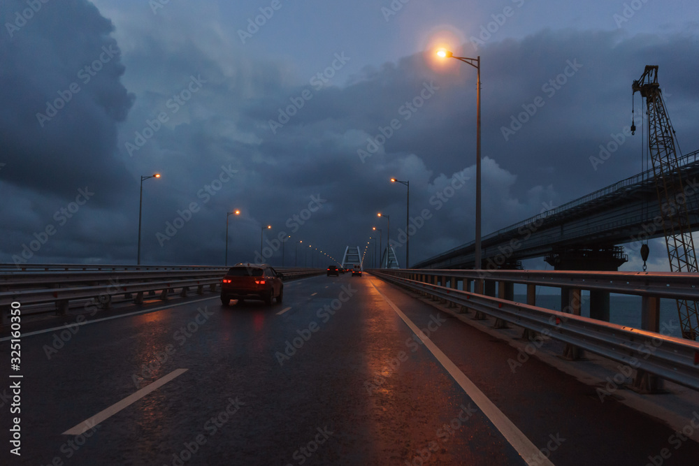 Cars drive on the Crimean bridge in the late evening