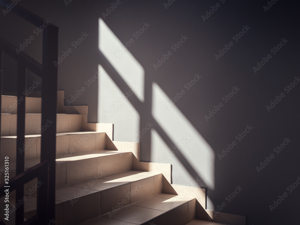 View of the bright steps illuminated by the sun and with a reflecting window in the form of a shadow on the wall View of the bright steps illuminated by the sun and with a reflecting window in the form of a shadow on the wall