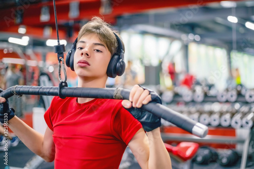 young man in sportswear and headphones trains in the gym