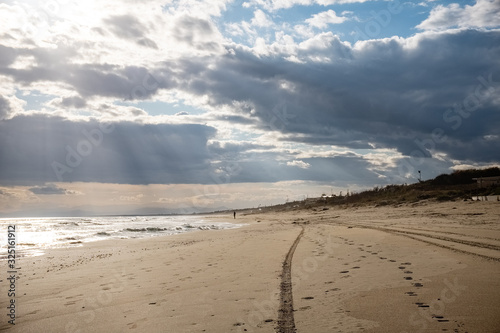 Tyre tracks disappearing into the horizon on a golden sand beach. Puglia region  Italy