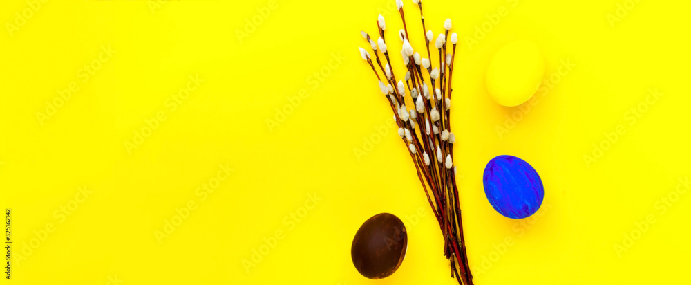 Fototapeta premium Colorful easter eggs and willow branches on yellow background. Festive concept, minimalism. Close-up