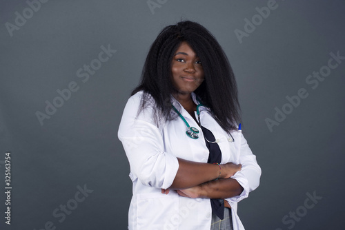 African American doctor girl happy face smiling with crossed arms looking confident at the camera standing against gray wall. Positive person.