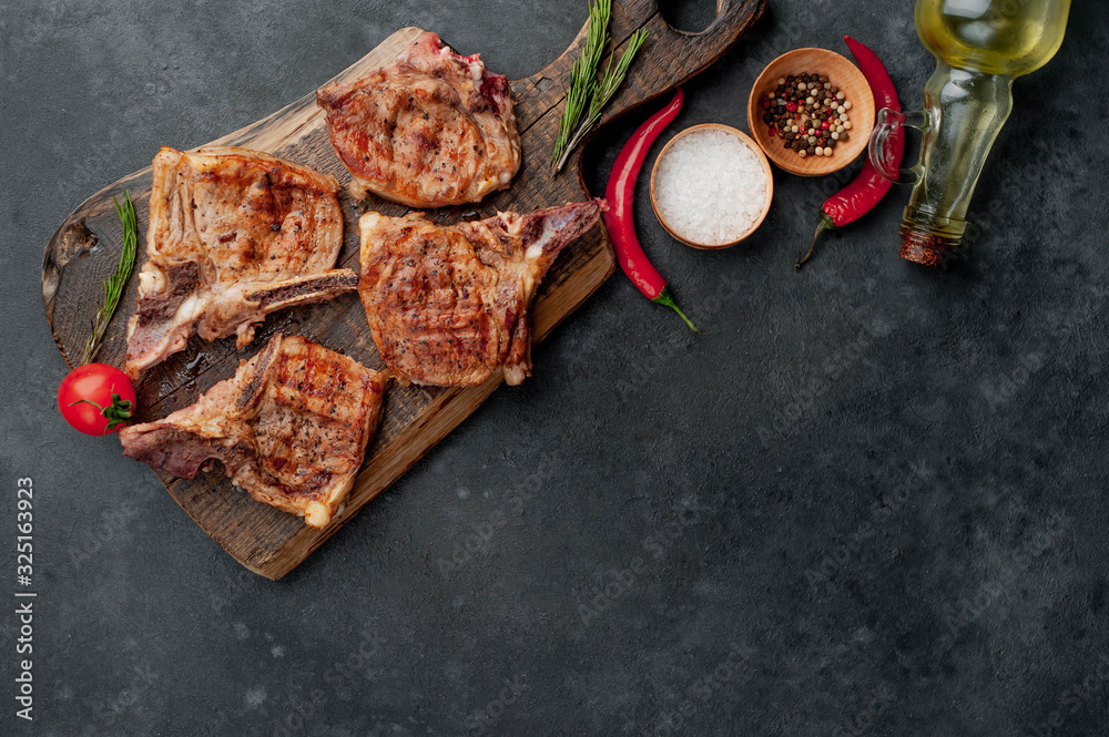 grilled beef steaks with spices on a cutting board on a stone background with copy space for your text grilled beef steaks with spices on a cutting board on a stone background with copy space for your text