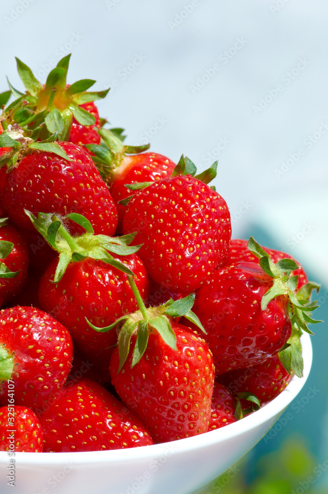 Ripe bright sweet strawberries in a white bowl in summer on a sunny day Ripe bright sweet strawberries in a white bowl in summer on a sunny day
