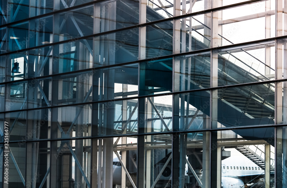 View on the modern glass facade with escalator at the airport. Modern architecture, glass and metal.