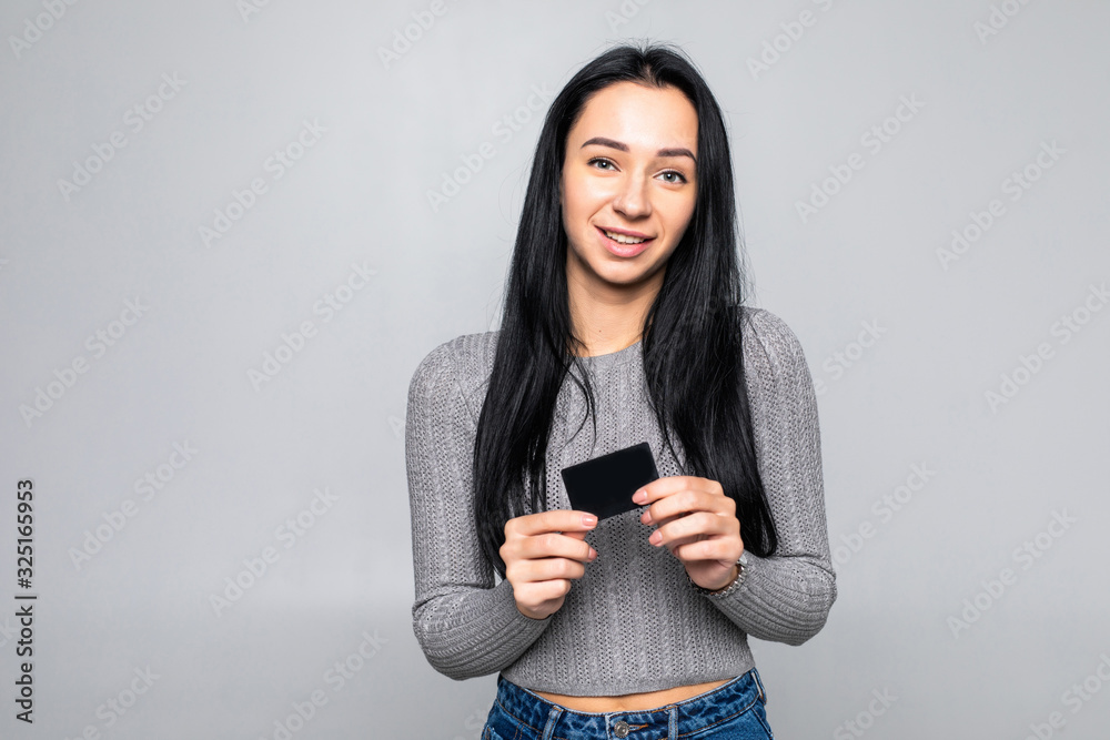 Portrait of young happy woman holding credit card against gray background. Portrait of young happy woman holding credit card against gray background.